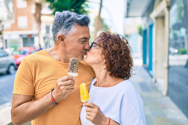 Couple d'âge moyen manger de la crème glacée et embrasser dans la rue de la ville. - Photo, image