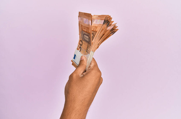 Mano hispana sosteniendo billetes de 50 euros sobre fondo rosa aislado. - Foto, imagen