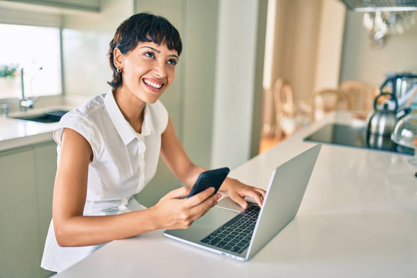 Schöne brünette Frau mit kurzen Haaren zu Hause mit Computer-Laptop - Foto, Bild