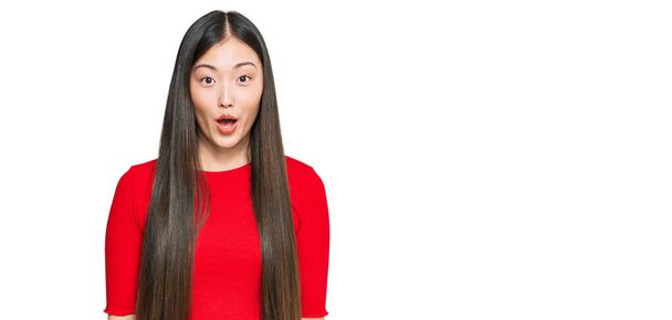 Jonge Chinese vrouw draagt casual kleding bang en geschokt met verrassende uitdrukking, angst en opgewonden gezicht.  - Foto, afbeelding