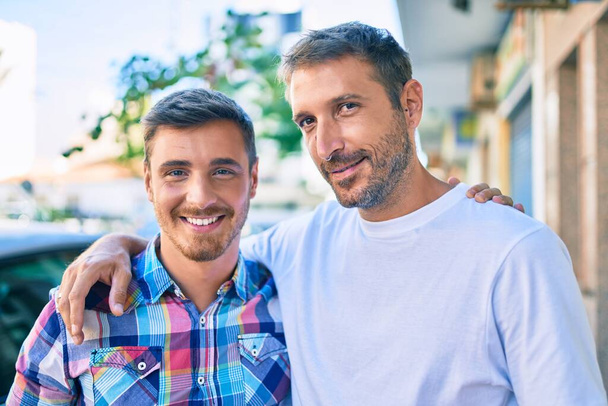 Mladý homosexuální pár usměvavý šťastný a objímající ve městě. - Fotografie, Obrázek