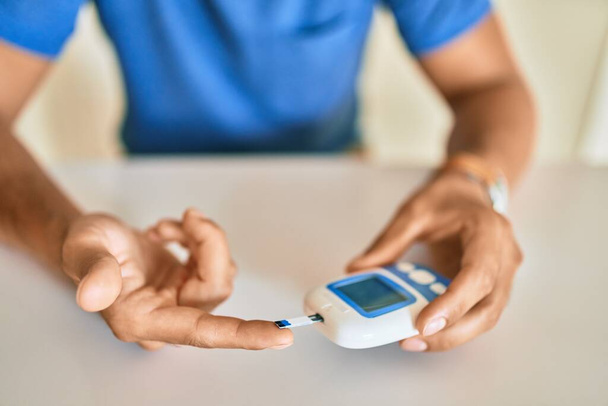 Jonge Latijns-Amerikaanse diabeticus die thuis glucosespiegel meet - Foto, afbeelding