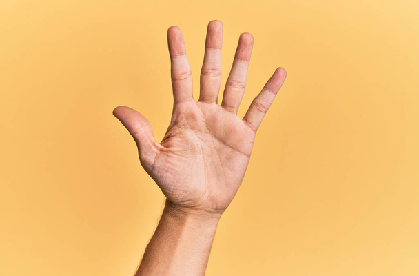 Paže a ruka bělocha přes žluté izolované pozadí počítání číslo 5 ukazující pět prstů  - Fotografie, Obrázek