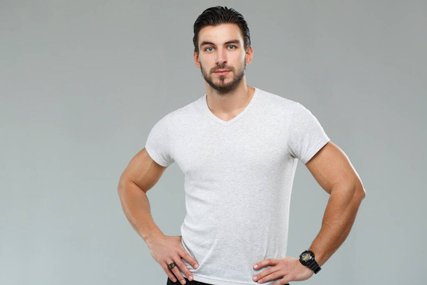 Attractive athletic man in a white shirt isolated on gray background. - Foto, Imagem
