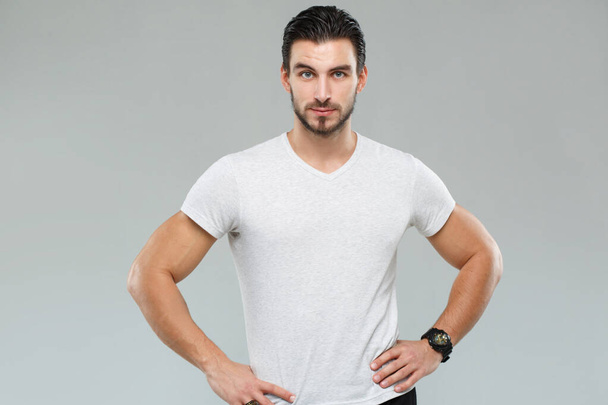 Attractive athletic man in a white shirt isolated on gray background. - Foto, immagini