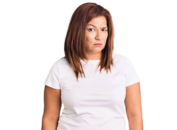 Латиноамериканка средних лет в обычной белой футболке скептически и нервно, хмурясь расстроена из-за проблем. отрицательный человек.  - Фото, изображение