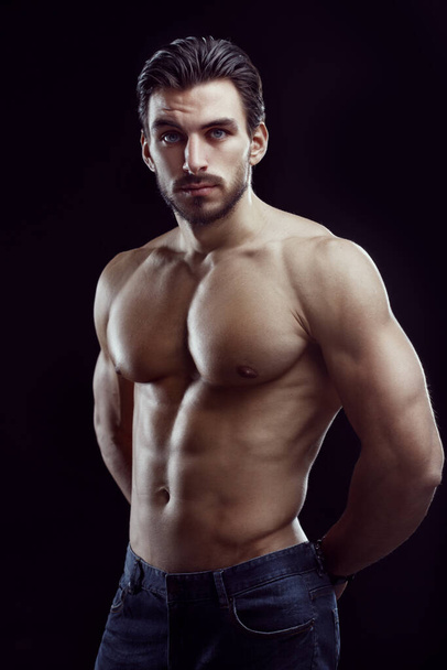 Portrait of an athletic man with a naked torso on a black background. - Fotoğraf, Görsel