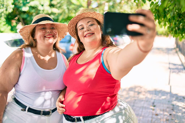 Dvě plus velikost nadváha sestry dvojčata ženy s úsměvem se selfie obrázek s telefonem venku na slunný den - Fotografie, Obrázek