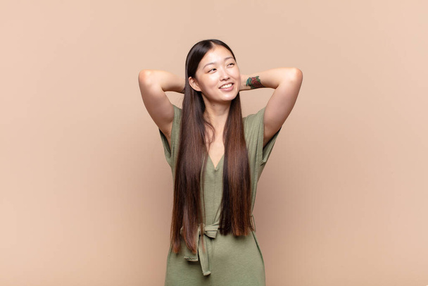asian young woman smiling and feeling relaxed, satisfied and carefree, laughing positively and chilling - Foto, imagen