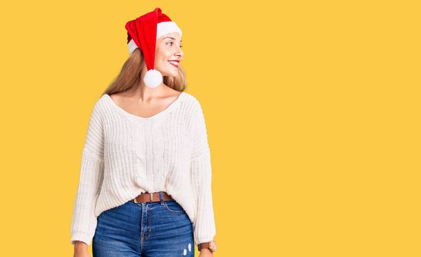 Kaunis nuori nainen yllään joulu hattu katselee sivuun hymyillen kasvot, luonnollinen ilme. nauraen luottavainen.  - Valokuva, kuva