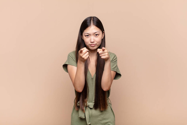 asian young woman pointing forward at camera with both fingers and angry expression, telling you to do your duty - 写真・画像