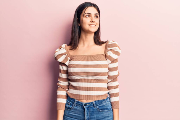 Young beautiful girl wearing casual striped t shirt looking to side, relax profile pose with natural face and confident smile.  - Photo, image