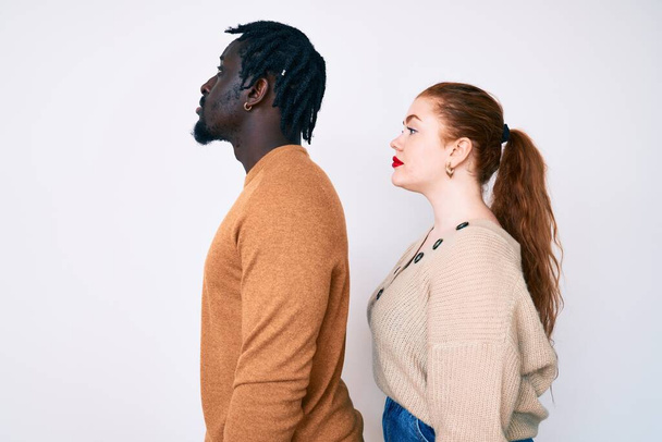 Interracial couple wearing casual clothes looking to side, relax profile pose with natural face and confident smile.  - Foto, Imagem