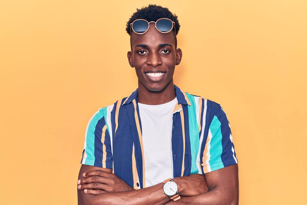 Young african american man wearing summer clothes and sunglasses happy face smiling with crossed arms looking at the camera. positive person.  - Photo, image