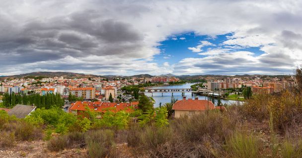Αστικό τοπίο της πόλης Mirandela στο βόρειο τμήμα της Πορτογαλίας. Πανοραμική θέα στις όχθες του ποταμού Τούα με την παραδοσιακή ρωμαϊκή γέφυρα και το ιστορικό κέντρο με τον πύργο της εκκλησίας του. - Φωτογραφία, εικόνα