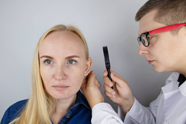 Darwinova tuberkulóza na uchu. Dívka na recepci u plastického chirurga, ukazuje auricle. - Fotografie, Obrázek