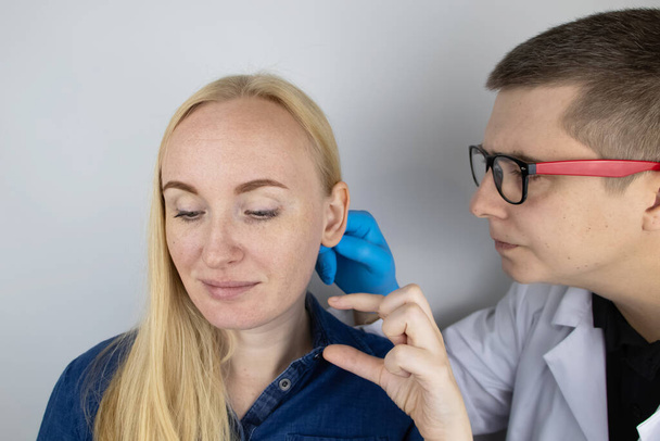 La chica está hablando con un cirujano plástico. Consulta con un médico sobre la remodelación del oído. - Foto, imagen