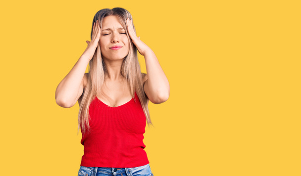 Young beautiful blonde woman wearing casual clothes suffering from headache desperate and stressed because pain and migraine. hands on head.  - Photo, Image