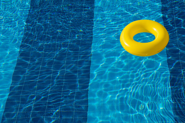 Желтый бассейн плавает, кольцо плавает в переливающемся голубом бассейне - Фото, изображение