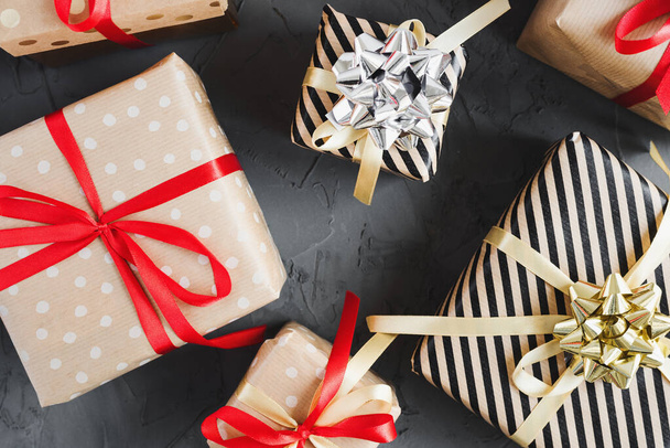 Cajas de regalo envueltas en papel artesanal con cintas rojas y amarillas sobre fondo de hormigón, vista superior. Navidad y Año Nuevo regalos - Foto, imagen