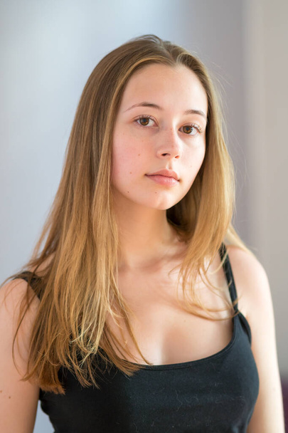 Retrato de una linda adolescente con una camiseta negra posando mirando a la cámara sobre un fondo gris - Foto, Imagen