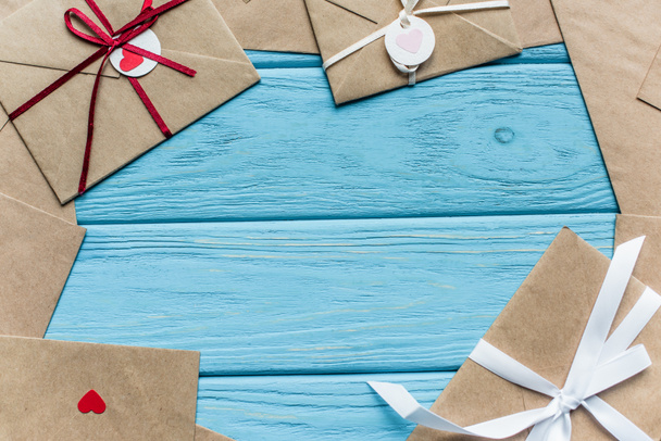 верхний вид деревянного синего фона с конвертами и сердцами - Фото, изображение