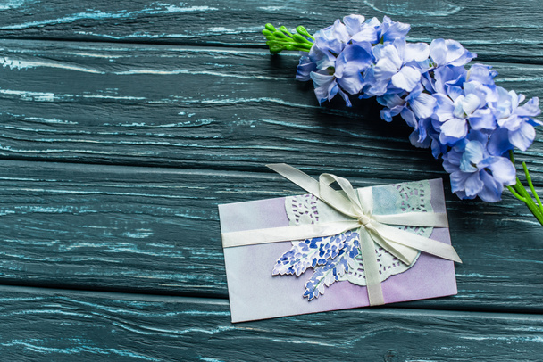 top view of wooden green background with blue flowers and envelope - Фото, изображение
