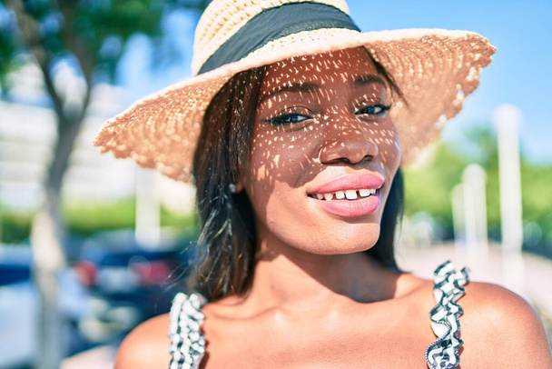Genç Afro-Amerikan kadın tatilde gülümsüyor ve şehrin sokaklarında mutlu bir şekilde yürüyor. - Fotoğraf, Görsel