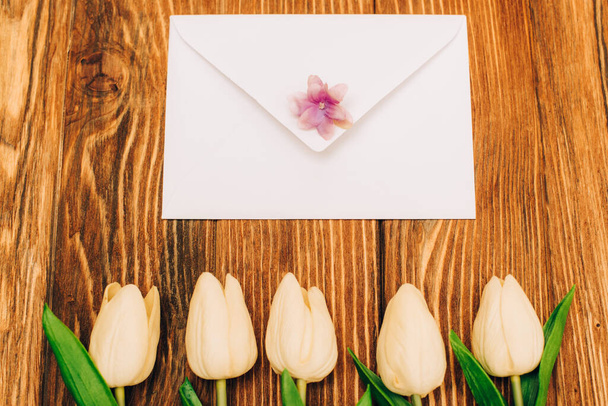 top view of envelope near tulips on wooden background - Фото, изображение