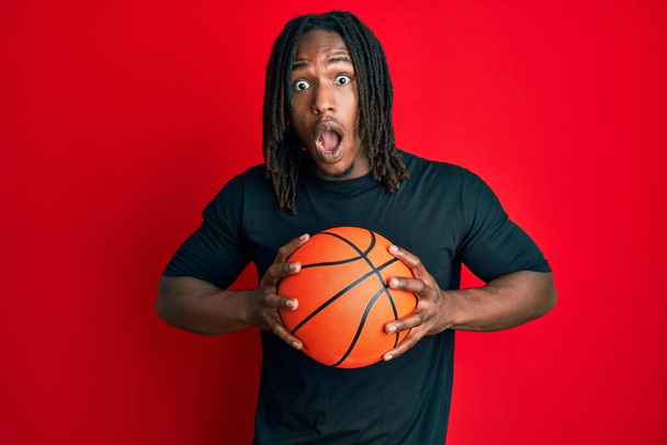 アフリカ系アメリカ人の男は、バスケットボールボールを持っている編組は恐れていると驚きと驚きの表情でショックを受けました,恐怖と興奮した顔.  - 写真・画像