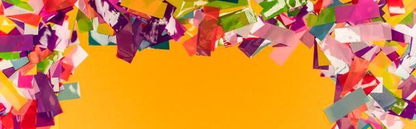 πάνω όψη πολύχρωμο φωτεινό πλαίσιο κομφετί σε πορτοκαλί φόντο, πανοραμική λήψη - Φωτογραφία, εικόνα