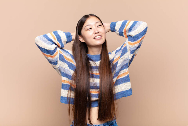 asian young woman smiling and feeling relaxed, satisfied and carefree, laughing positively and chilling - Photo, image