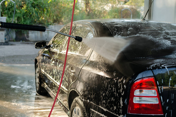 Auto in der Selbstbedienungswaschanlage, Reinigung und Waschen des schwarzen Autos, Nahaufnahme - Foto, Bild