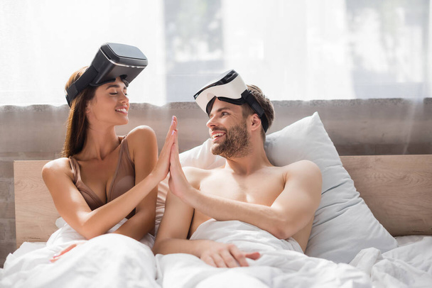 юные влюбленные с гарнитурами VR смотрят друг на друга и дают высокую пятерку - Фото, изображение