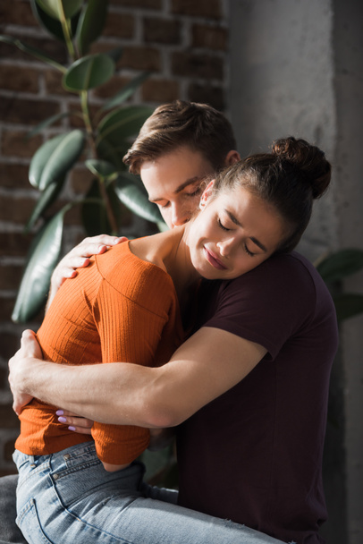 Junger Mann umarmt und beruhigt Freundin weinend zu Hause - Foto, Bild
