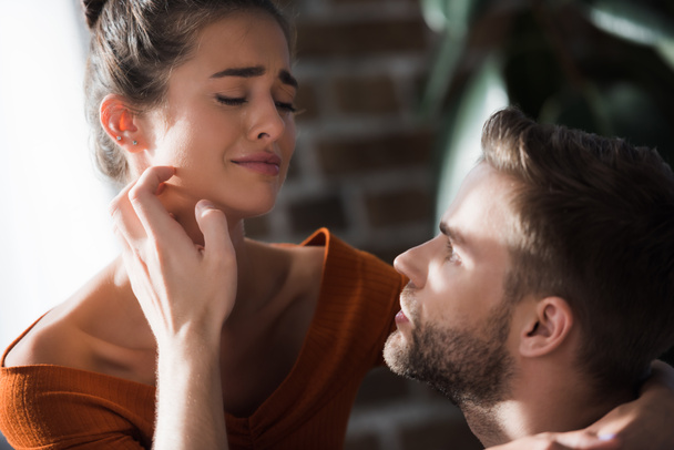 tender man touching face of crying girlfriend while calming her at home - Foto, Bild