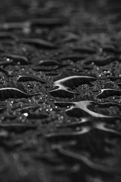 Σκούρο γκρι φόντο μαύρο σχιστόλιθο με σταγόνες νερού ή φυσική πέτρινη υφή. Μαύρη πλακέτα για κοντινό σέρβις. Σταγόνες νερού από κοντά σε μαύρο φόντο - Φωτογραφία, εικόνα