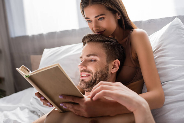 sexy young couple reading book in bedroom together - Zdjęcie, obraz