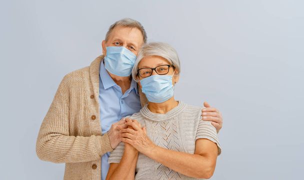 Senior couple wearing facemask during coronavirus and flu outbreak. Virus and illness protection, home quarantine. COVID-2019. Taking on masks. - Photo, Image
