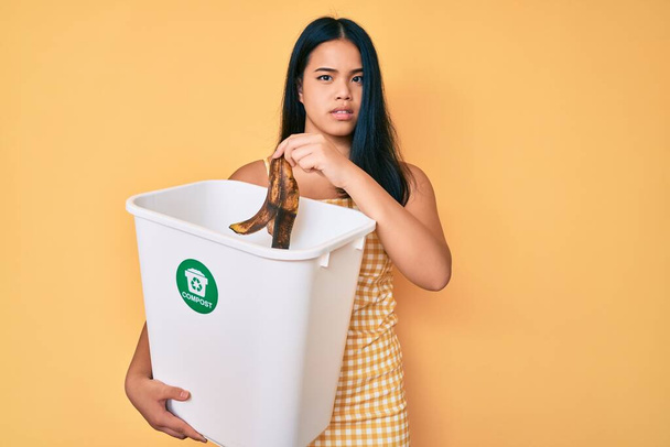 Junges asiatisches Mädchen beim Recycling von Lebensmittelkompostierung organischem Dünger ahnungslos und verwirrt. Zweifelhaftes Konzept.  - Foto, Bild