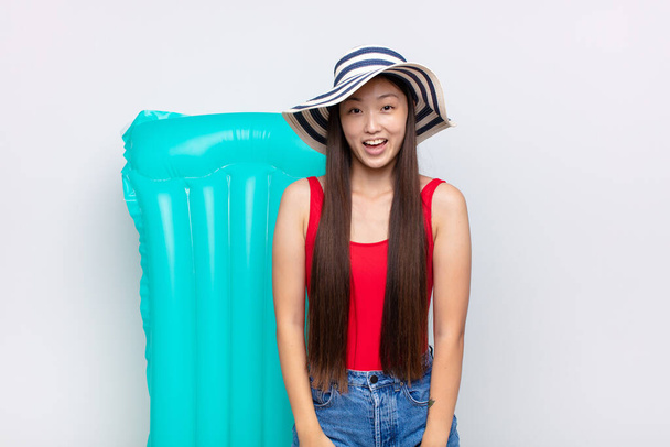 asian young woman looking happy and pleasantly surprised, excited with a fascinated and shocked expression. summer concept - Photo, Image