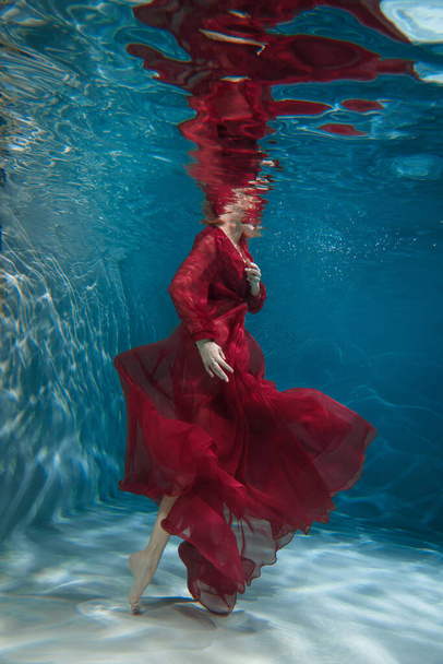 Female figure in a dark red dress underwater. - Zdjęcie, obraz