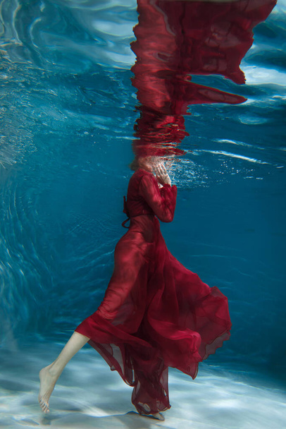 Female figure in a dark red dress underwater. - Foto, Imagem