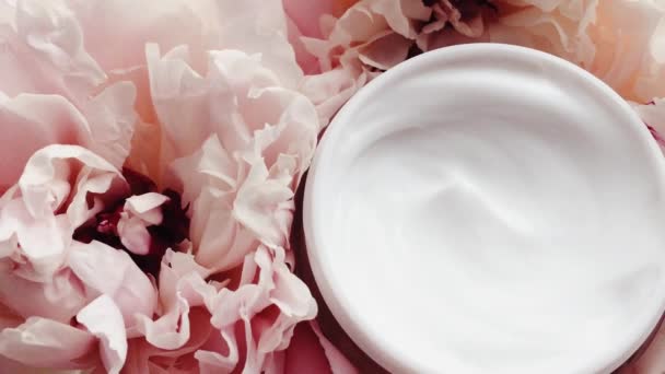 Biologische gezichtscrème pot en pioenroos bloemen, schone vochtinbrengende crème als huidverzorging routine voor luxe cosmetische, beauty product en huidverzorgingsmerk - Video