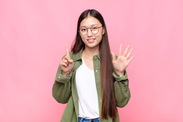 asian young woman smiling and looking friendly, showing number six or sixth with hand forward, counting down - Foto, immagini