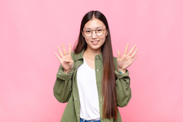 asian young woman smiling and looking friendly, showing number nine or ninth with hand forward, counting down - Φωτογραφία, εικόνα