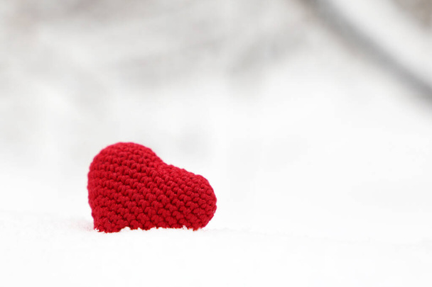 Valentine heart in winter forest, selective focus. Red knitted heart in the snow, background for Christmas card or Valentine's day - Φωτογραφία, εικόνα