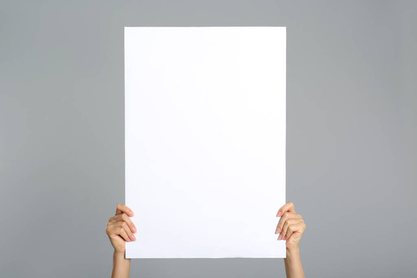 Woman holding white blank poster on grey background, closeup. Mockup for design - Φωτογραφία, εικόνα