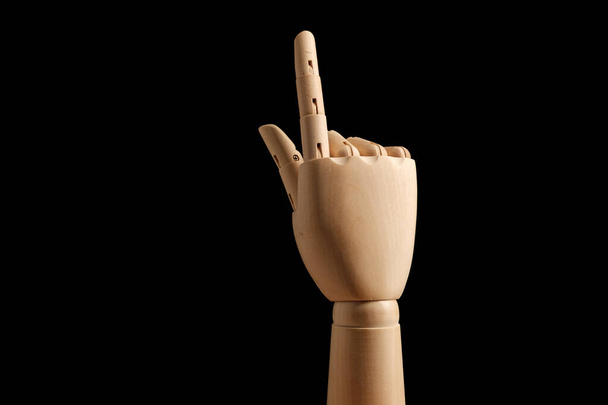 Wooden hand of mannequin for drawing indicates the direction of the index finger on a black background. Learning to count - one. Art model for drawing. Part of the body - hand, brush. Swipe up - Foto, imagen