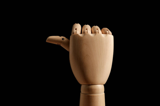 Drewniany ręka manekin dla rysunek pokazuję z kciuk kierunek na czarny tło. Ręczny wskaźnik. Widok z boku. Model do rysowania. Część ciała - dłoń, szczotka. - Zdjęcie, obraz